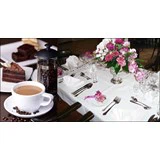 En kop kaffe med kage på den ene side og et elegant dækket spisebord med blomster på den anden side.