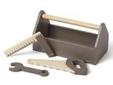 Et legetøjsværktøjskassesæt i træ med bærehåndtag, lineal, skruenøgle og sav, alt sammen i neutrale brune og beige farver.