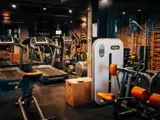 Et moderne fitnesscenter med løbebånd, vægtmaskiner, bænke og frie vægte, med murstensvægge og dæmpet belysning.
