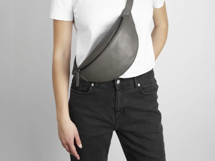 Personen var iført en hvid t-shirt og sorte jeans og havde en grå læderbæltetaske over brystet.