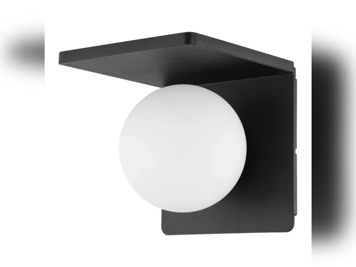 En moderne væglampe med en sort metalramme og en rund, hvid lyskugle, monteret i en vinkel.