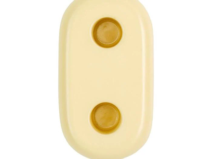 Et beige, ovalt objekt med to runde, brunlige knapper eller fordybninger, der er placeret lodret i midten.