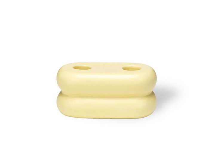 Et lysegult, afrundet, rektangulært objekt med to huller på toppen, der ligner stablede puder eller bløde blokke, på en hvid baggrund.