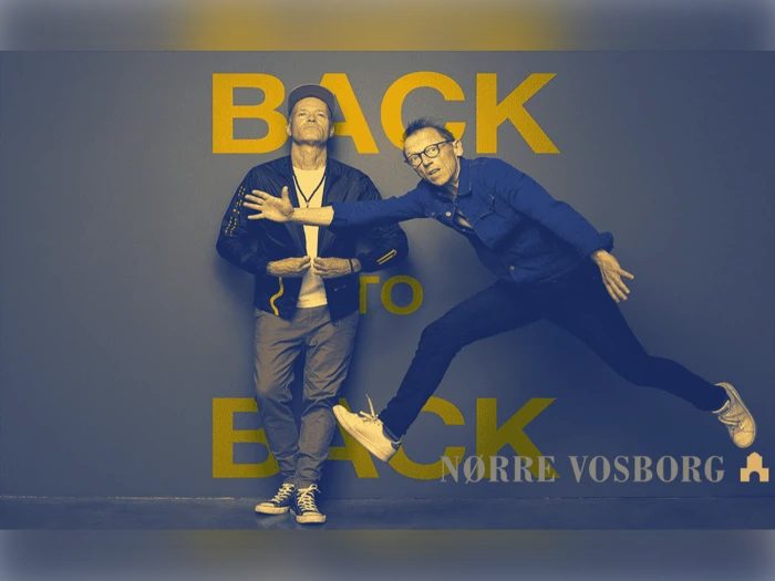 To mænd poserer foran en væg med ordene BACK TO BACK. Den ene står med korslagte arme, mens den anden hopper energisk med et bøjet ben og spredte arme.