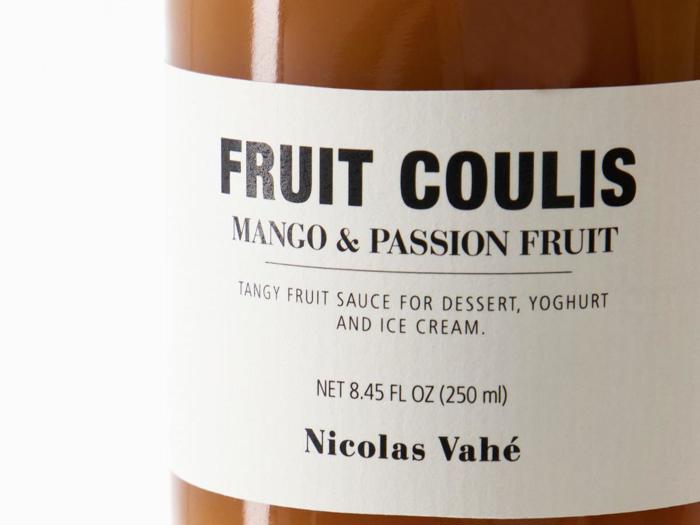 Et nærbillede af en krukke mærket FRUIT COULIS Mango & Passion Fruit af Nicolas Vahé, der beskrives som en syrlig frugtsauce til dessert, yoghurt og is.