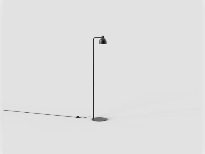 En minimalistisk sort gulvlampe med et slankt ben og en lille, afrundet lampeskærm på en cirkulær fod.
