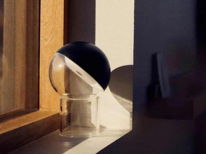 En kugle af klart glas med en sort halvdel står på en vindueskarm og kaster en karakteristisk skygge i det bløde naturlige lys.