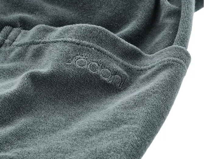 Nærbillede af et struktureret mørkegråt stof med synlige syninger og ordet joom broderet på.