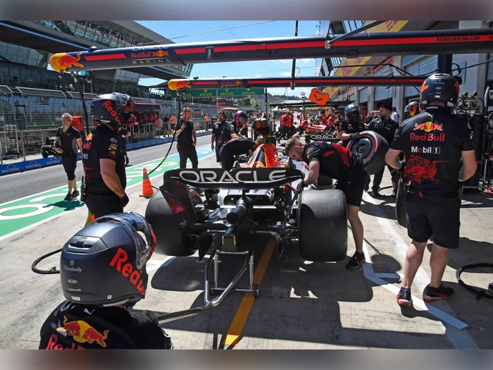 Red Bull Racings Formel 1-team udfører et pitstop på en racerbil i pitlane, hvor besætningsmedlemmer arbejder på dæk og udstyr.