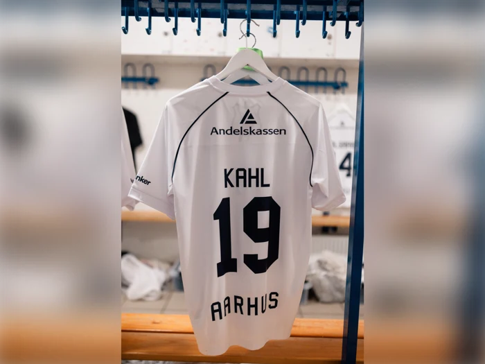 En hvid fodboldtrøje, der hænger i et skab, med navnet KAHL, nummer 19 og AARHUS på ryggen.