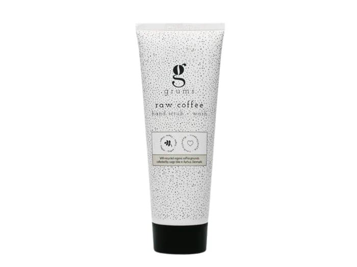 En hvid tube mærket grums raw coffee hand scrub + wash med en sort hætte, med minimalistisk design og små sorte prikker på emballagen.