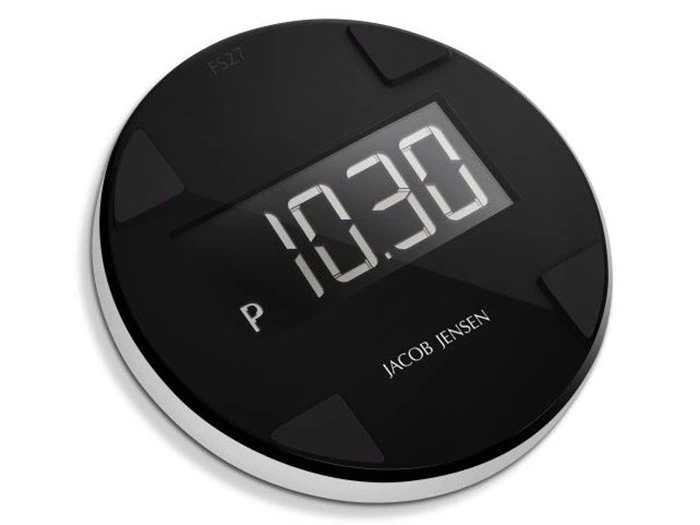 Et rundt, sort digitalt parkeringsur viser 10:30. Enheden har et slankt design med JACOB JENSEN-branding på overfladen.