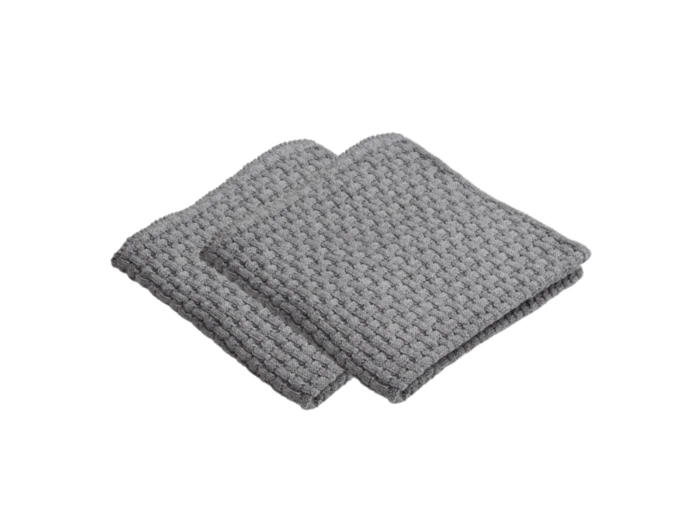 To foldede grå vaffelmønstrede vaskeklude stablet på en hvid baggrund.