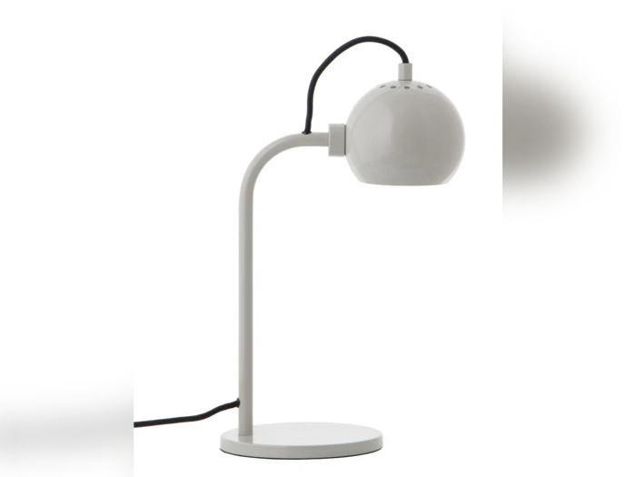 En moderne hvid skrivebordslampe med rund fod, buet arm og kugleformet lampeskærm. En sort netledning strækker sig fra toppen af lampen.
