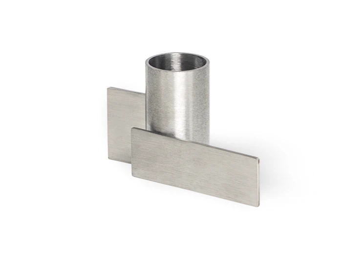 Et cylindrisk metalrør krydser to flade, rektangulære metalplader i rette vinkler mod en hvid baggrund.