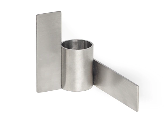 En metalgenstand med et centralt cylindrisk rør og to flade rektangulære plader, der skærer hinanden i rette vinkler på hver side.