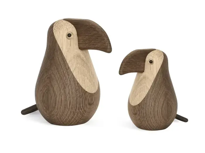 To fuglefigurer af træ med store næb over for hinanden, en større og en mindre, lavet af lyst og mørkt træ.