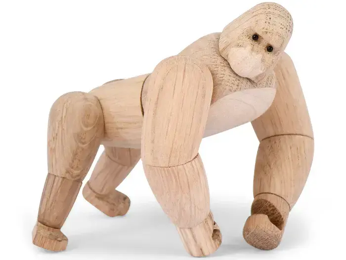 En gorillafigur af træ står på alle fire med bevægelige led og en glat, naturlig finish.