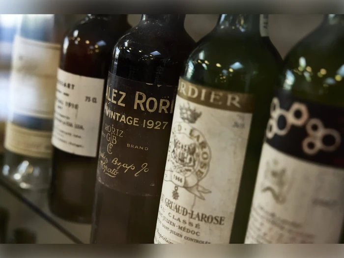 En række årgangsvinflasker på en hylde, bl.a. en González Roriz fra 1927 og en Château Gruaud-Larose Saint-Julien-Médoc, med gamle, slidte etiketter.