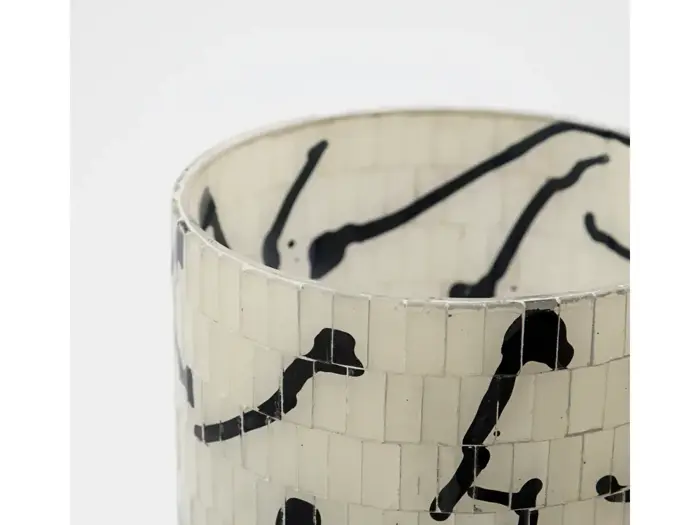 Et nærbillede af et cylindrisk objekt med en hvid flisebelagt overflade og abstrakte sorte linjer, der danner et mønster.