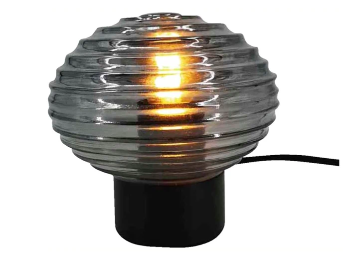 En tændt bordlampe med en rund, riflet glasskærm og en sort, cylindrisk fod, som udsender et varmt lys.