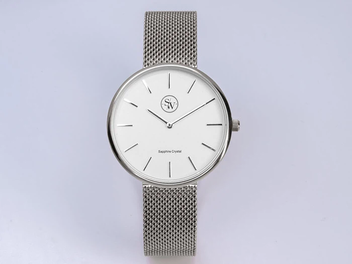 Et minimalistisk sølvfarvet armbåndsur med hvid urskive, tynde timemarkeringer, mesh-rem og safirglas på skiven.