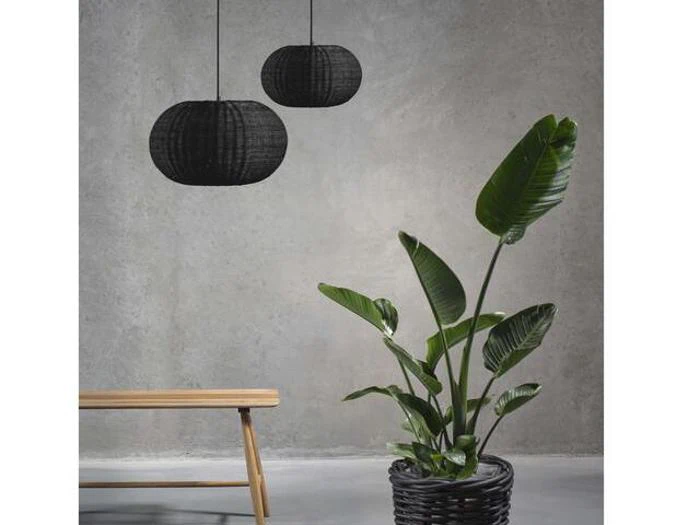 Et moderne rum med en træbænk, to sorte pendler og en stor grøn potteplante mod en grå betonvæg.