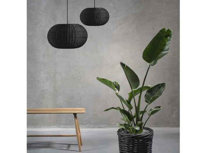 En grøn potteplante står ved siden af en træbænk under to sorte pendellamper, alt sammen mod en almindelig grå væg.