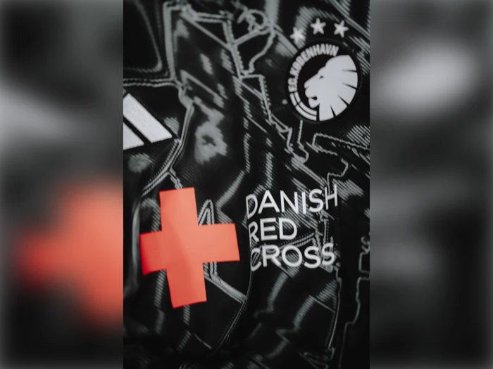 Nærbillede af en sort fodboldtrøje med FC Københavns logo, et rødt kors og teksten Dansk Røde Kors i hvidt.