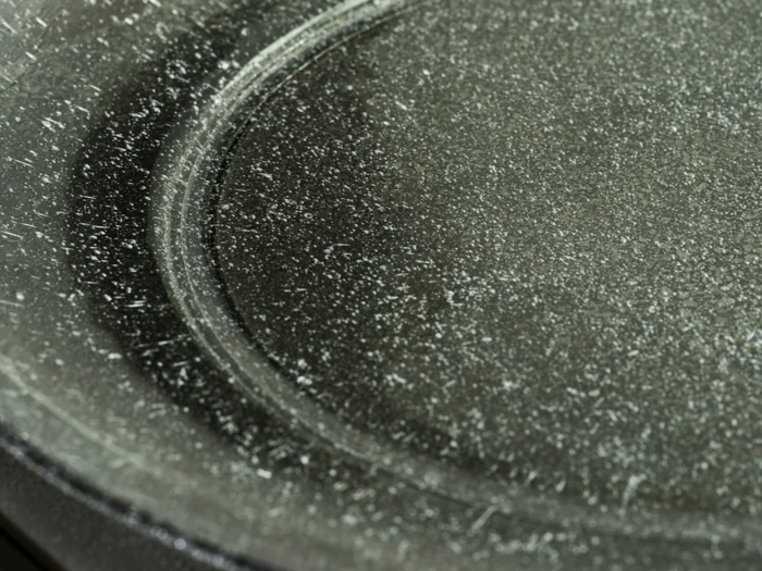 Nærbillede af en sort non-stick-pande med mange hvide ridser og skrammer på overfladen.