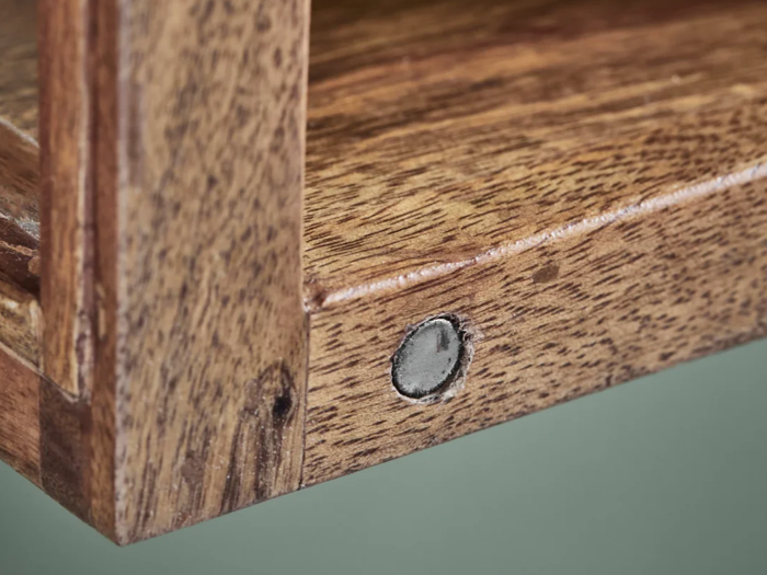 Nærbillede af et hjørne af en træhylde, hvor man kan se en rund metalskrue, der holder de to stykker træ sammen.