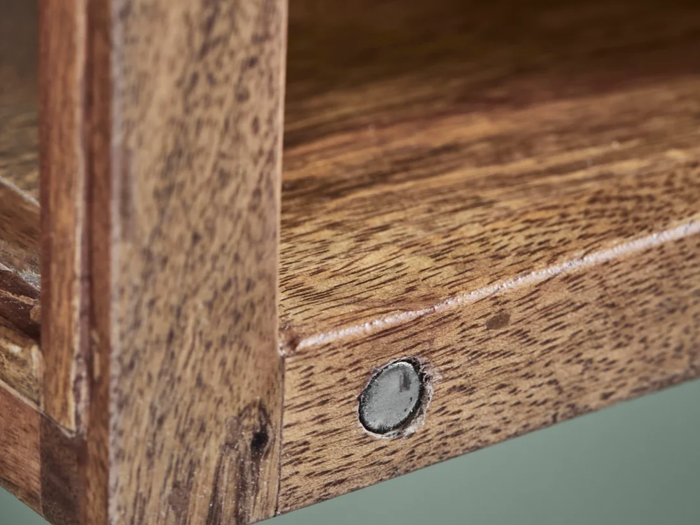 Nærbillede af et træhyldehjørne med en synlig metalskrue, der er indlejret i træets årer og fremhæver strukturen og konstruktionsdetaljerne.