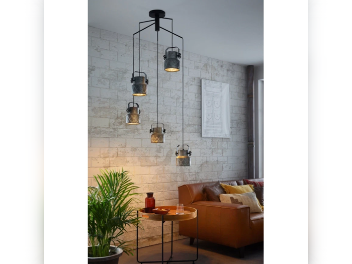 En moderne stue med en brun sofa, planter, et lille rundt bord og et unikt hængende lysarmatur med flere lanternelignende lamper i forskellige højder.