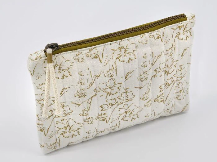 En cremefarvet stofpose med et blomstermønster i guld og en lynlås i guld, vist på en almindelig hvid baggrund.