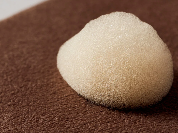 Et nærbillede af en lille bunke hvidt skum, der hviler på en struktureret brun overflade.