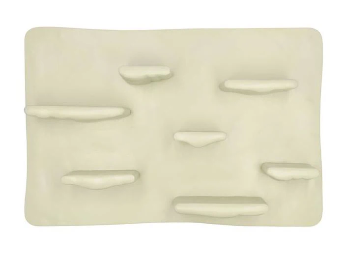 Et rektangulært, råhvidt vægpanel med flere afrundede, kantlignende fremspring, der er placeret ujævnt på overfladen.
