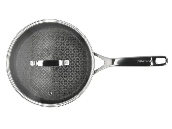 En stegepande i rustfrit stål med en sort struktureret nonstick-overflade og et glaslåg, set ovenfra.