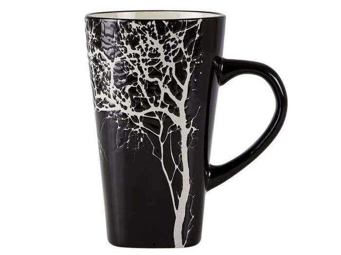 Et højt sort keramikkrus med en hvid træsilhuet på siden og en buet hank.