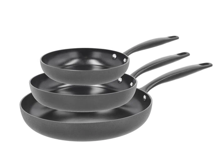 Tre sorte nonstick-stegepander i forskellige størrelser stablet sammen, hver med et langt sort håndtag vendt mod højre.