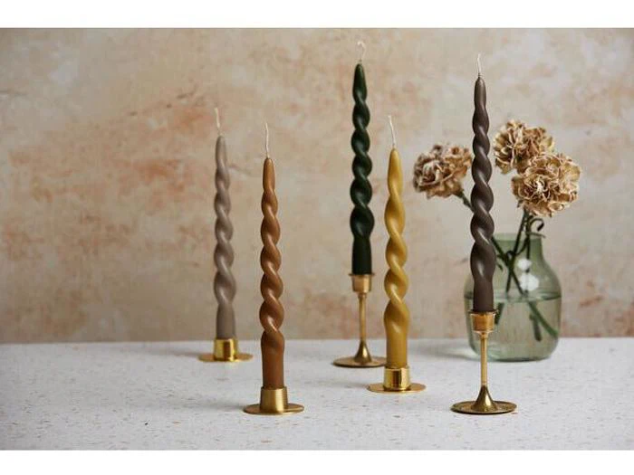 Fem snoede kertelys i forskellige jordfarver står i guldholdere på en plettet overflade med tørrede blomster i en glasvase i baggrunden.