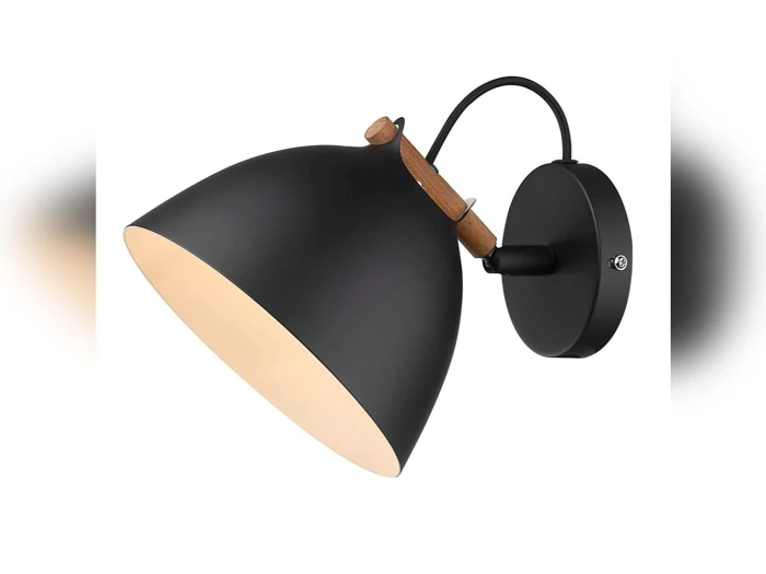 En moderne sort væghængt lampe med træaccent og en bred, kuppelformet skærm, der udsender et varmt lys.