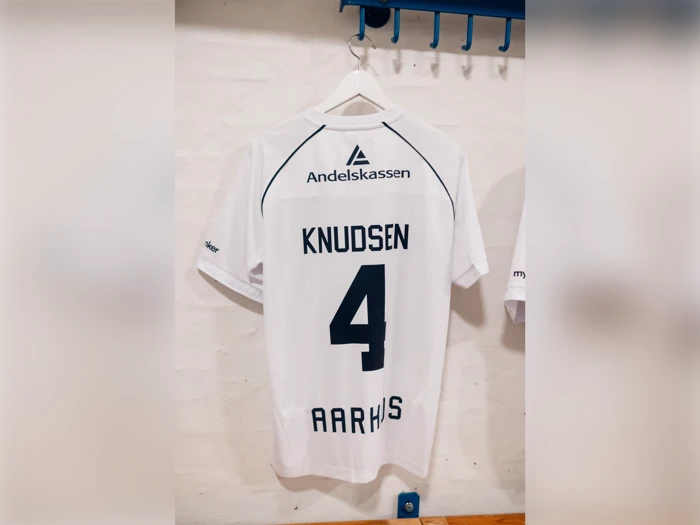 Hvid fodboldtrøje med KNUDSEN og tallet 4 på ryggen, med Andelskassen-logoet og teksten AARHUS.