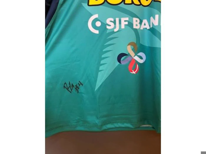 En turkis sportstrøje med en signatur med nummer 4, SJF Bank-logoet og et farverigt firkløver-emblem.
