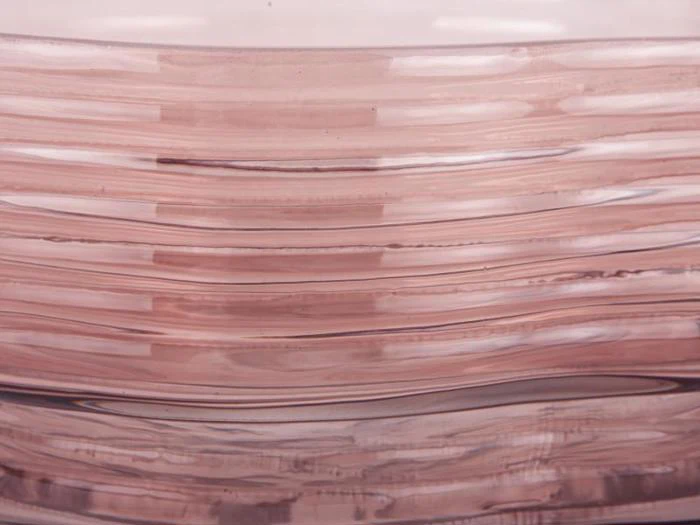 Nærbillede af et gennemskinneligt, rosa materiale med lagdelte, bølgede vandrette linjer, der skaber et abstrakt mønster.