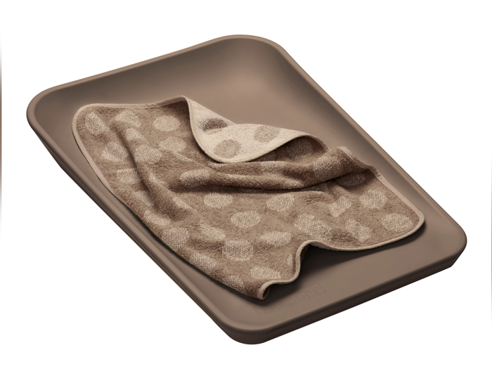 En beige rektangulær bakke med et lysebrunt håndklæde med polkaprikket mønster, delvist foldet, placeret indeni.