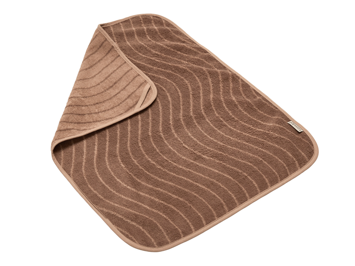 Et brunt rektangulært håndklæde med buede, bølgelignende mønstre, hvor det ene hjørne er foldet om for at vise bagsiden.