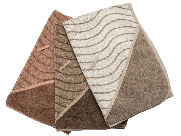 Tre foldede håndklæder i farverne brun, tan og beige med bølgelinjemønstre, lagt side om side på en hvid baggrund.