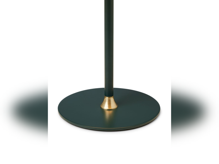 Et nærbillede af en lampe- eller standerfod med en rund, mørkegrøn platform med en guldaccent, hvor stangen møder foden, mod en hvid baggrund.