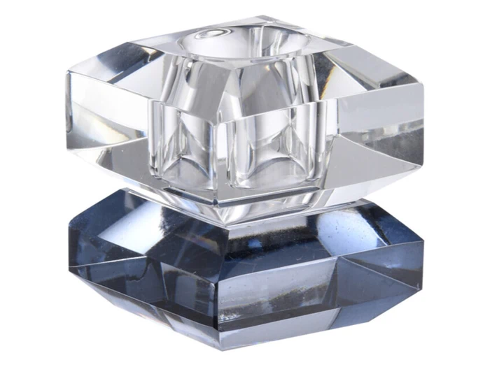 Et geometrisk, facetteret glas- eller krystalobjekt med klare og mørke sektioner, der ligner et moderne dekorativt stykke eller en brevvægt, fotograferet mod en hvid baggrund.