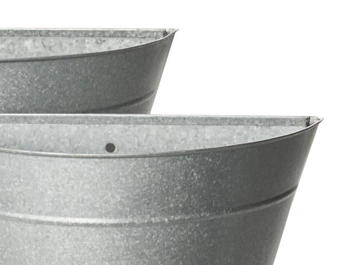 Nærbillede af to grå, galvaniserede metalbeholdere med en buet, spandlignende form mod en hvid baggrund.